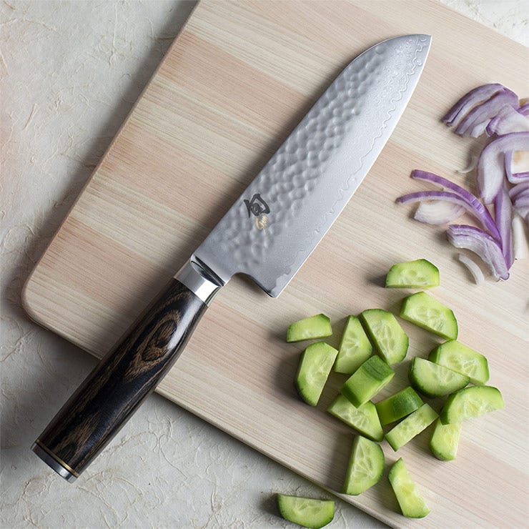 A Premier Santoku lies next to a pile of diced cucumbers.