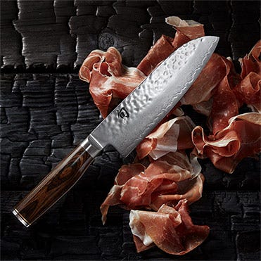 A Premier 7" Santoku lies on a bed of thinly sliced meat.