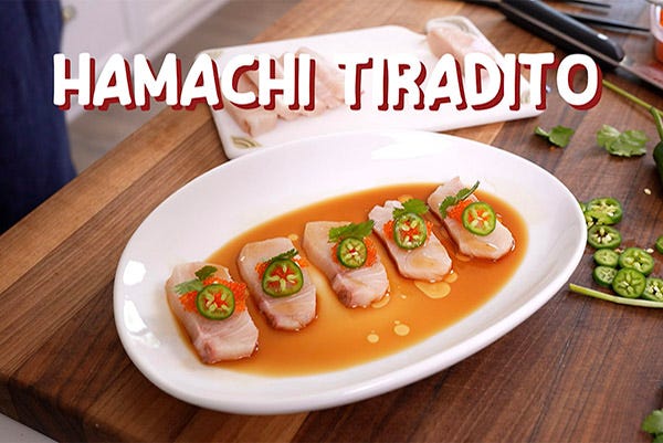 Sliced hamachi on a plate with sliced chilis and ponzu sauce