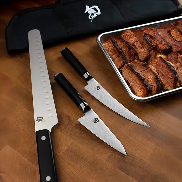 A Classic BBQ Set is shown laid out on a table next to a sheet pan full of sliced brisket.
