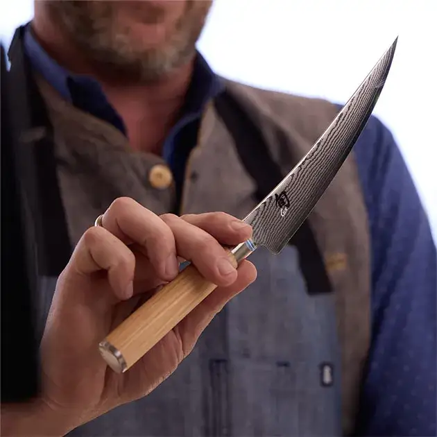 A chef holds a Classic Blonde Boning & Fillet Knife up to the camera.