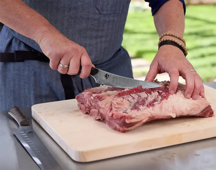 A pitmaster uses a Kanso boning & fillet knife to remove silver skin.