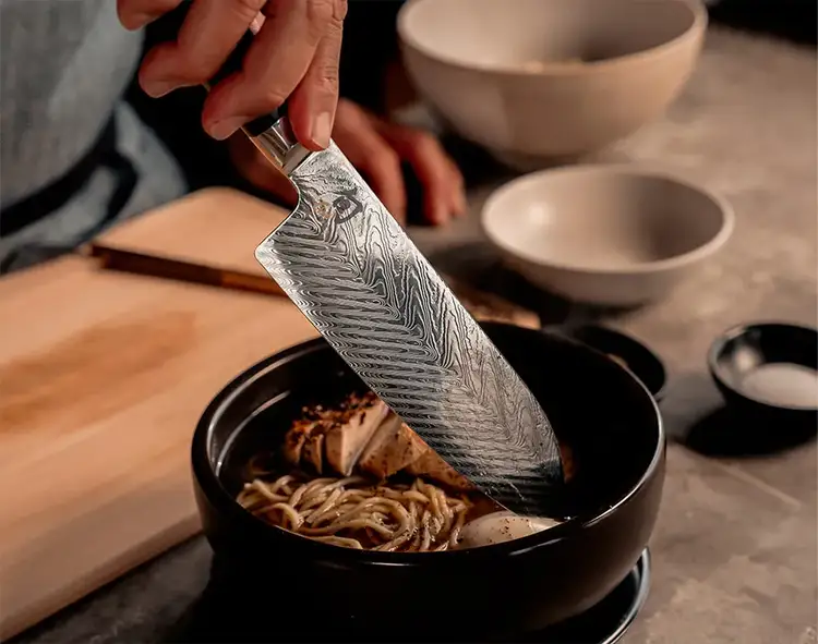 A Dual Core Santoku is dipped into a bowl of ramen.